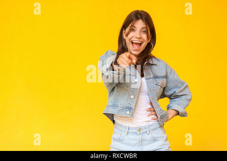 Portrait von überrascht schöne Brünette junge Frau mit Make-up in Denim lässige Stil stehen, zeigen und auf Kamera mit entsetzten Gesicht. die Pflege von Stockfoto