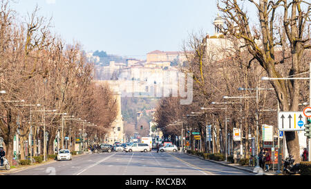 BERGAMO, Italien - 19 Februar 2019: Menschen und Autos auf der Straße Viale Papa Giovanni XXIII und der Skyline von Oberstadt. Bergamo ist die Hauptstadt der Provinz Stockfoto