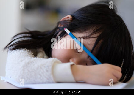 Asiatisches junges Kind Einschlafen während der Studie Stockfoto