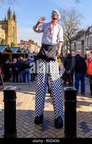 Super-Chef (Mann auf Stelzen) winkt für Kamera, die durch die Stände und Menschen an der Wakefield Essen, Trinken & Rhabarber Festival 2019, Yorkshire, England, UK. Stockfoto