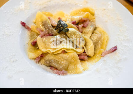 Italienische Küche - Casoncelli im Stil alla Bergamasca (Pasta mit Semmelbrösel, Ei, Parmesan, Rinderhack, Salami gefüllt) auf die weiße Platte in Loca Stockfoto