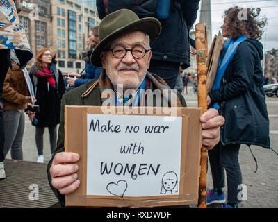 Amsterdam, Nordholland, Niederlande. 9 Mär, 2019. Ein alter Mann wird gesehen, Sitzen, während sie ein Plakat, Nein zu sagen, Krieg mit Frauen während des Protestes. Einen Tag nach dem Internationalen Frauentag eine Demonstration unter dem Motto "Alle Unterdrückung verbunden ist, fand im Zentrum von Amsterdam. Hunderte von Menschen, die an der Dam Platz versammelt, um eine Erklärung für ihre Rechte, die sie sind, auch ein Leben ohne Angst, mit Respekt, gleiche Bezahlung und gleiche Recht auf Gerechtigkeit, unabhängig von Hautfarbe, Einkommen, Religion oder der Fähigkeit zu machen. (Bild: © Ana Fernandez/SOPA Bilder über Z Stockfoto