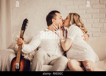 Junge, glücklich verheiratete Paar küssen Sitzen auf der Couch Stockfoto