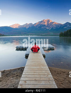 Mann auf dem Dock meditieren im Pyramid Lake, Jasper National Park, Alberta, Kanada. Stockfoto