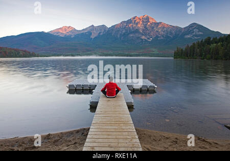 Mann auf dem Dock meditieren im Pyramid Lake, Jasper National Park, Alberta, Kanada. Stockfoto