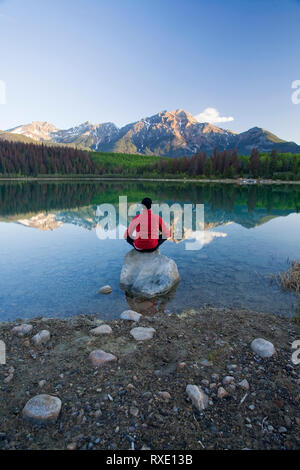 Mittleres Alter Mann Meditation am frühen Morgen im Pyramid Lake, Jasper National Park, Alberta, Kanada. Stockfoto