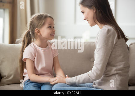 Liebevolle Mutter und Kind halten sich an den Händen sprechen, sitzen auf dem Sofa Stockfoto