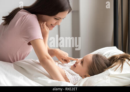 Glückliche Mutter zärtlich Aufwachen cute kid Tochter im Bett Stockfoto