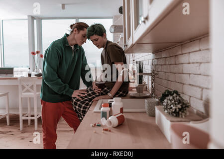 Mann tragen grüne Jacke seine betonte Frau unterstützen. Stockfoto