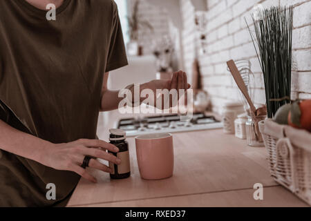 Frau mit Pillen in ihrem Palm steht in der Küche Stockfoto