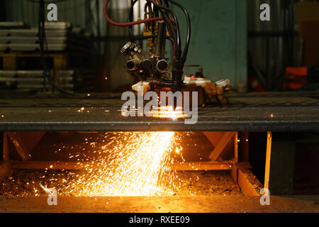 Die Maschine schneidet Bleche mit Gas. Flying spray geschmolzenes Metall. Von der Seite. Stockfoto