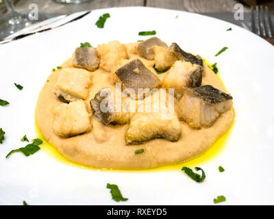 Italienische Küche - Teil der Baccala (Stockfisch) mit Creme von Kichererbsen auf weiße Platte in einem lokalen Restaurant in der Lombardei Stockfoto