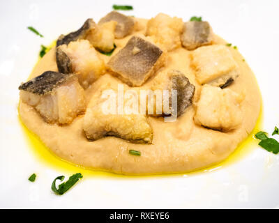 Italienische Küche - Stücke von Baccala (Stockfisch) mit Creme von Kichererbsen schließen bis auf weiße Platte in einem lokalen Restaurant in der Lombardei Stockfoto