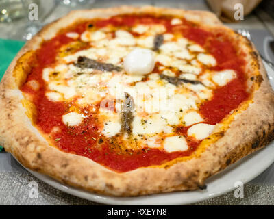 Typisch italienische Pizza Napoli mit Sardellen und Mozzarella überbacken im traditionellen Holzofen auf Platte in einem lokalen Restaurant in der Lombardei gefeuert Stockfoto