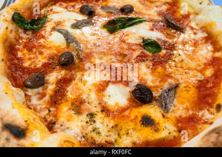 Traditionelle italienische Pizza Napoli mit Sardellen und Oliven Nahaufnahme gebacken in Holzofen in einem lokalen Restaurant in der Lombardei Stockfoto