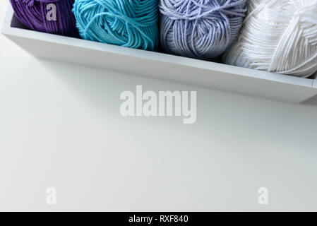 Ansicht von oben auf ein weißes Stück Holzbox mit farbigen Garnen Kugeln und kopieren Raum unter. Stockfoto