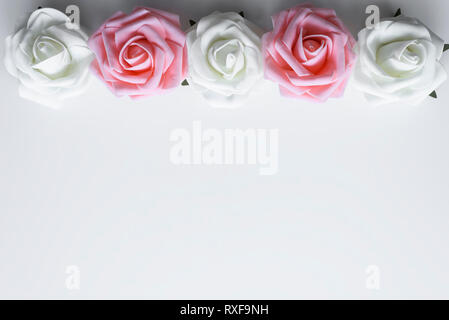 Wunderschöne Rosen in rosa und weiße Farbe als Top Linie angeordnet. Valentinstag oder Muttertag Blumen Dekoration, mit Kopie Raum auf weißem Hintergrund. Stockfoto