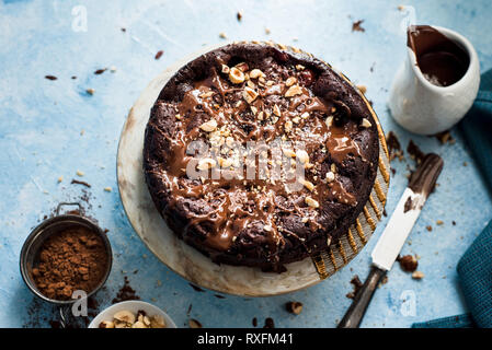 Schokoladenkuchen auf einer runden Platte mit gehackten Haselnüssen Stockfoto