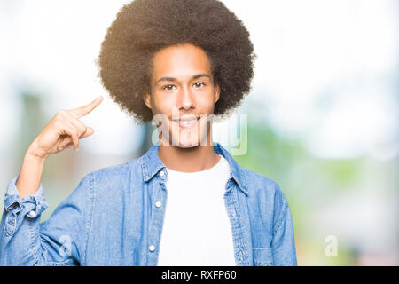 Junge afrikanische amerikanische Mann mit afro Haar Lächeln zeigte mit einem Finger zu Kopf, tolle Idee oder gedacht, gutes Gedächtnis Stockfoto