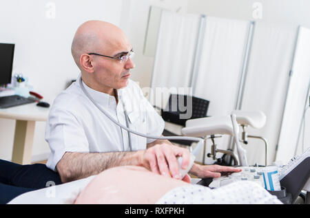 Das Foto zeigt einen Gynäkologen, der eine schwangere Patientin per Ultraschall untersucht Stockfoto