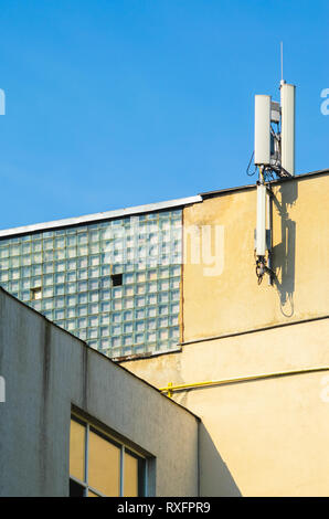Mobilfunkbetreiber Antennen auf der Oberseite der Fassade eines Industriegebäudes gegen den blauen Himmel. Kopieren Sie Platz. Kommunikationstechnik Con Stockfoto
