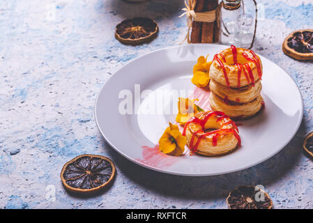 Horizontale Foto mit mehreren Donuts aus Blätterteig Teig. Red Topping Erdbeer ist auf Ringe verschüttet. Donuts sind auf weiße Platte mit Fe platziert Stockfoto