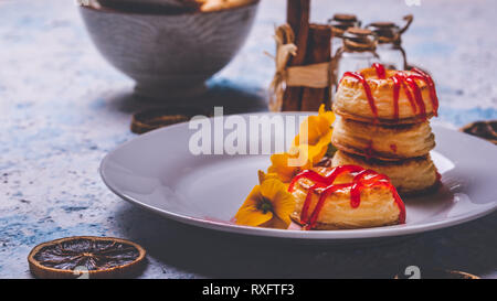 Horizontale Foto mit mehreren Donuts aus Blätterteig Teig. Red Topping Erdbeer ist auf Ringe verschüttet. Donuts sind auf weiße Platte mit Fe platziert Stockfoto
