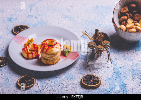 Horizontale Foto mit mehreren Donuts aus Blätterteig Teig. Red Topping Erdbeer ist auf Ringe verschüttet. Donuts sind auf weiße Platte mit Fe platziert Stockfoto