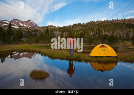 Wanderer und Zelt in einem Alpinen See in der Nähe von Broken Top Mountain außerhalb Schlaufe Oregon widerspiegelt Stockfoto