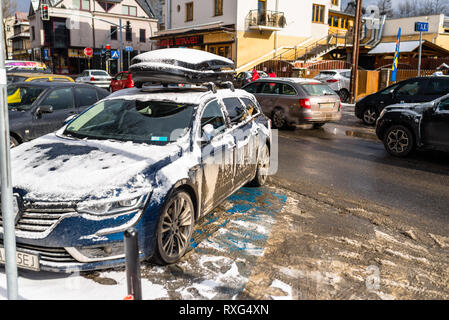 Zakopane, Polen - 22. Februar 2019. Ein schmutziges und verschneiten Auto stehend auf einem Parkplatz an einer belebten, städtische Straße. Foto im Winter, städtische Bauen Stockfoto