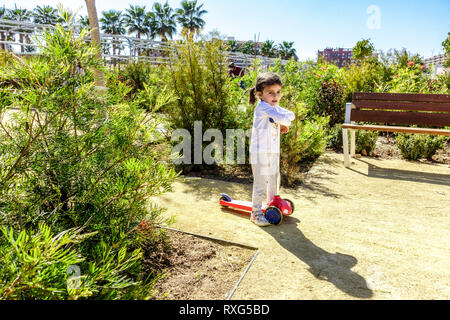 Valencia Central Park, ein kleines Mädchen auf einem Schubroller in einem Garten, Spanien Europa Valencia Park Garten Kleinkind allein Stockfoto