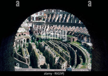 Das historische Foto durch einen Torbogen zeigt das Innere der Römischen Kolosseum 1963 vor Restaurationen unterwegs, die fast 2000 Jahre alte ovale Amphitheater aus in mehr verfallen im Herzen von Rom, Italien fallen zu bewahren. In der Arena Holzboden, die einmal die unterirdischen Gänge und Räume, in denen Gladiatoren und wilden Tiere gewartet hatten, bevor ihre Kämpfe seit teilweise rekonstruiert worden. Und Treppen jetzt bieten den Besuchern den Zugang zu den oberen Stockwerken untergebracht, viele Tausende von Zuschauern im größten Amphitheater der Welt. Foto von Michele & Tom Grimm urheberrechtlich geschützt Stockfoto