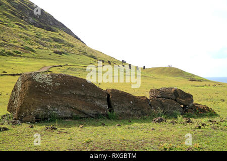 Bleibt der Moai Statue auf dem Boden liegend bei Rano Raraku Vorberg mit einer Gruppe von Moai auf der Piste im Hintergrund, Easter Island, Chile Stockfoto