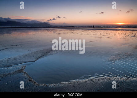 Einsamer Wanderer bei Sonnenuntergang, Dinas Dinlle Strand, Dinas Dinlle, Gwynedd, Wales, UK MODEL RELEASED Stockfoto