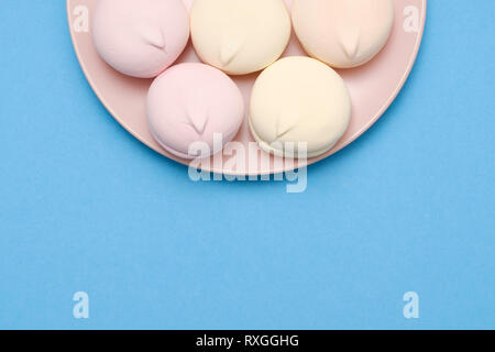 Marshmallows auf Platte auf blauem Hintergrund mit Copyspace. Flach oder der Ansicht von oben. Hintergrund oder Textur des Kreises Marshmallows. Stockfoto
