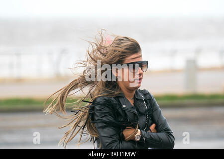 Blackpool, Großbritannien. 10. März, 2019. Strong gale force Winde an der Küste. Shopper sind windswept als der starke Stürmische Winde fegen durch die Innenstadt. Wetter Warnungen haben sich über den Nordwesten von England für schwere Böen und Starkregen über das Wochenende ausgestellt wurde. . Credit: MediaWorldImages/Alamy leben Nachrichten Stockfoto