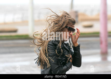Blackpool, Großbritannien. 10. März, 2019. Strong gale force Winde an der Küste. Shopper sind windswept als der starke Stürmische Winde fegen durch die Innenstadt. Wetter Warnungen haben sich über den Nordwesten von England für schwere Böen und Starkregen über das Wochenende ausgestellt wurde. . Credit: MediaWorldImages/Alamy leben Nachrichten Stockfoto