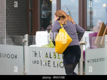 Blackpool, Großbritannien. 10. März, 2019. Strong gale force Winde an der Küste. Shopper sind windswept als der starke Stürmische Winde fegen durch die Innenstadt. Wetter Warnungen haben sich über den Nordwesten von England bei starken Windböen und Regen über das Wochenende ausgestellt wurde. . Credit: MediaWorldImages/Alamy leben Nachrichten Stockfoto