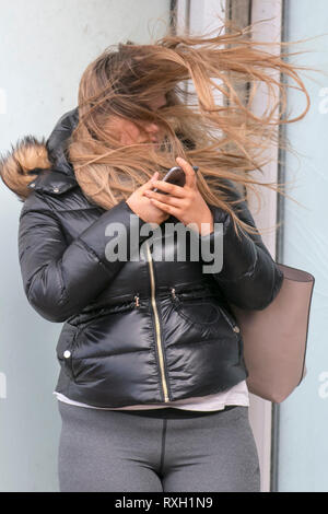 Blackpool, Großbritannien. 10. März, 2019. Strong gale force Winde an der Küste. Shopper sind windswept als der starke Stürmische Winde fegen durch die Innenstadt. Wetter Warnungen haben sich über den Nordwesten von England für schwere Böen und Starkregen über das Wochenende ausgestellt wurde. . Credit: MediaWorldImages/Alamy leben Nachrichten Stockfoto