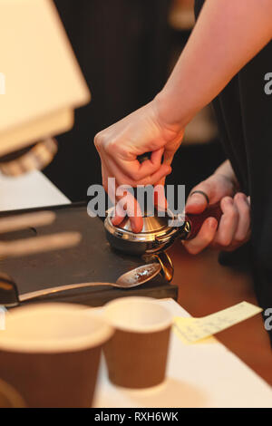 Kaffeemaschine. Frau Tempel frisch gemahlenen Kaffee in einen portafilter. getönt Stockfoto