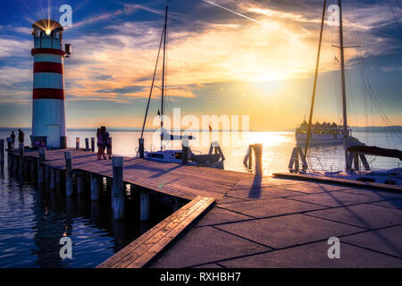 Österreich, Podersdorf, 09.12.2018: Leuchtturm am Neusiedler See bei Sonnenuntergang mit einem touristenboot kommt zurück zum Hafen. Podersdorf am See ist eine Gemeinde Stockfoto