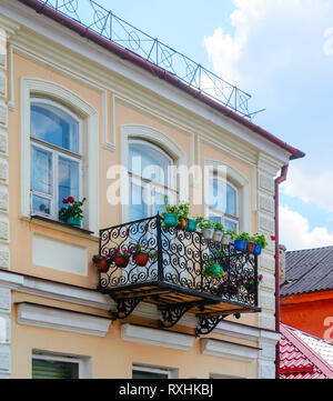 Gepflegte Fassade eines alten Gebäudes. Balkon mit blühenden Blumen Stockfoto
