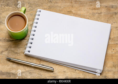 Leere Spirale Art Skizzenbuch gegen gegen strukturierte Rinde Papier mit einer Tasse Kaffee Stockfoto