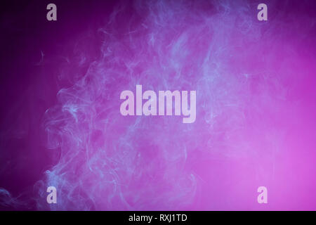 Nebel gefärbt mit hellen blauen Gel auf dunklem Rosa Hintergrund Stockfoto