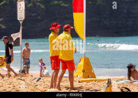 Freiwillige surf Rettungskräfte durch gelbe und rote Fahnen standen auf bilgola Beach, Sydney, Australien Stockfoto