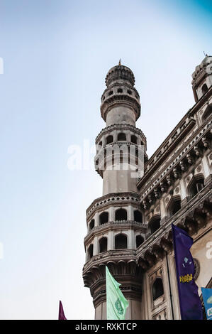 Eine Nahaufnahme eines der minarette von Charminar, "vier Minarette", Hyderabad, Telangana, Indien. Die verschiedenfarbigen Fahnen flattern im Vordergrund. Stockfoto