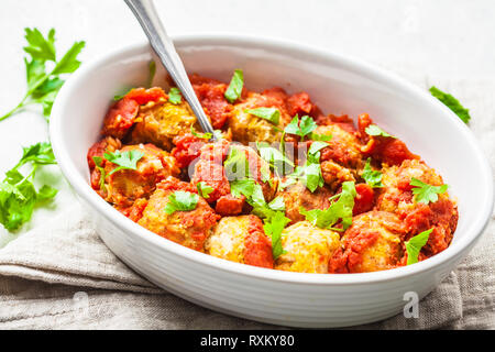 Gebackene vegan bean Hackfleischbällchen in Tomatensauce mit Petersilie in weißen Teller. Auf Basis pflanzlicher Nahrung Konzept. Stockfoto