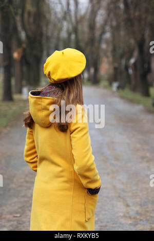 Mädchen in einem gelben Fell und Barett in Park Stockfoto