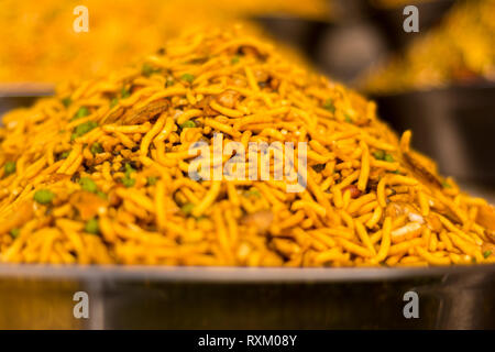 Gelb gefärbte namkeen in Stahl Platte gehalten in einem Geschäft im Tageslicht. Namkeen ist ein salziger Indischen Imbiss. Stockfoto