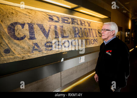 John Kelly, deren 17 Jahre alten Bruder, Michael, während der blutige Sonntag getötet wurde, steht neben der Derry Civil Rights Association Banner im Museum von Free Derry, dass an dem Tag, als blutiger Sonntag bekannt ist, durchgeführt wurde. Die Staatsanwaltschaft wird erwartet, zu verkünden, ob es Ermittlungen gegen Soldaten über den Tod von 13 Menschen in Londonderry am 30. Januar 1972 fortzusetzen. Stockfoto